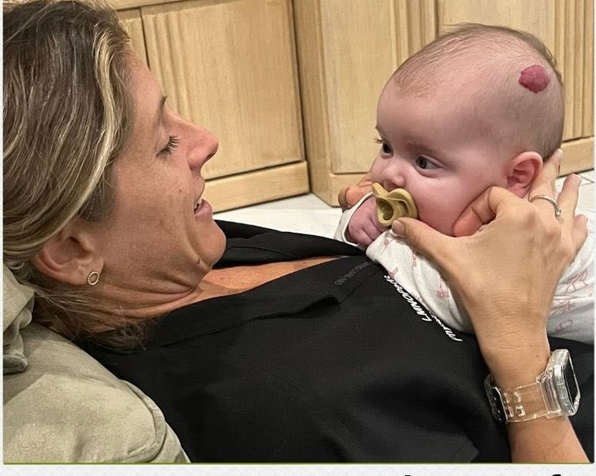 Baby doing tummy time propped upright on a parent's chest